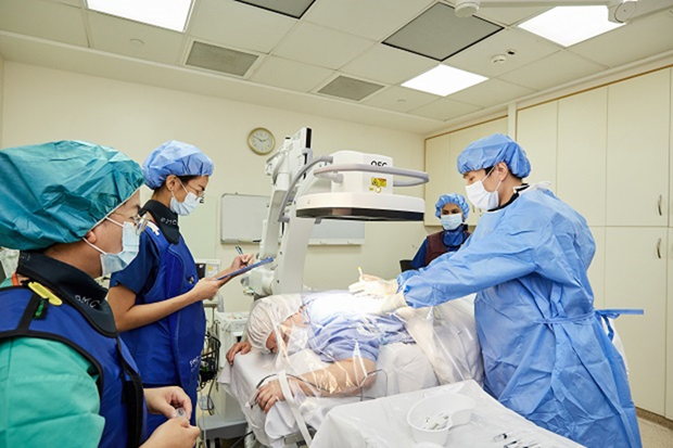  ​Dr Zhen Wei performs a staged procedure to dull pain in the spine. The nurses and radiographer wear protective vests as a fluoroscope is used to help pinpoint the exact area of pain.  Photo credit Vernon Wong 