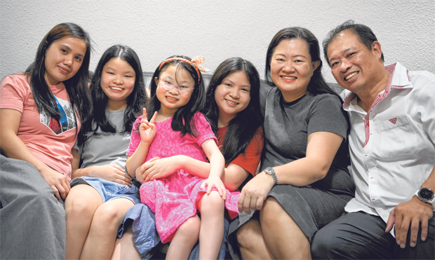  ​Nine-year-old Ng Hwee Suan (third from left), with her father Edwin Ng, mother Ivy Yeo, helper Lovelyne Ballogan, and elder sisters Ng Hwee Ling (second from left) and Ng Hwee Him, at home on Friday. Hwee Suan is only the second person here to have undergone an intestinal transplant. Her parents decided on the procedure, which was done on April 2, because of the amount of pain Hwee Suan had suffered in the past year. ST PHOTO MARK CHEONG