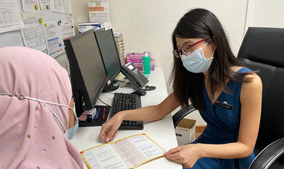  ​淡滨尼综合诊疗所家庭医学助理顾问阮淑慧医生（右）通过大肠癌决策手册，和病患讨论不同筛检方式。（新保集团综合诊疗所提供）