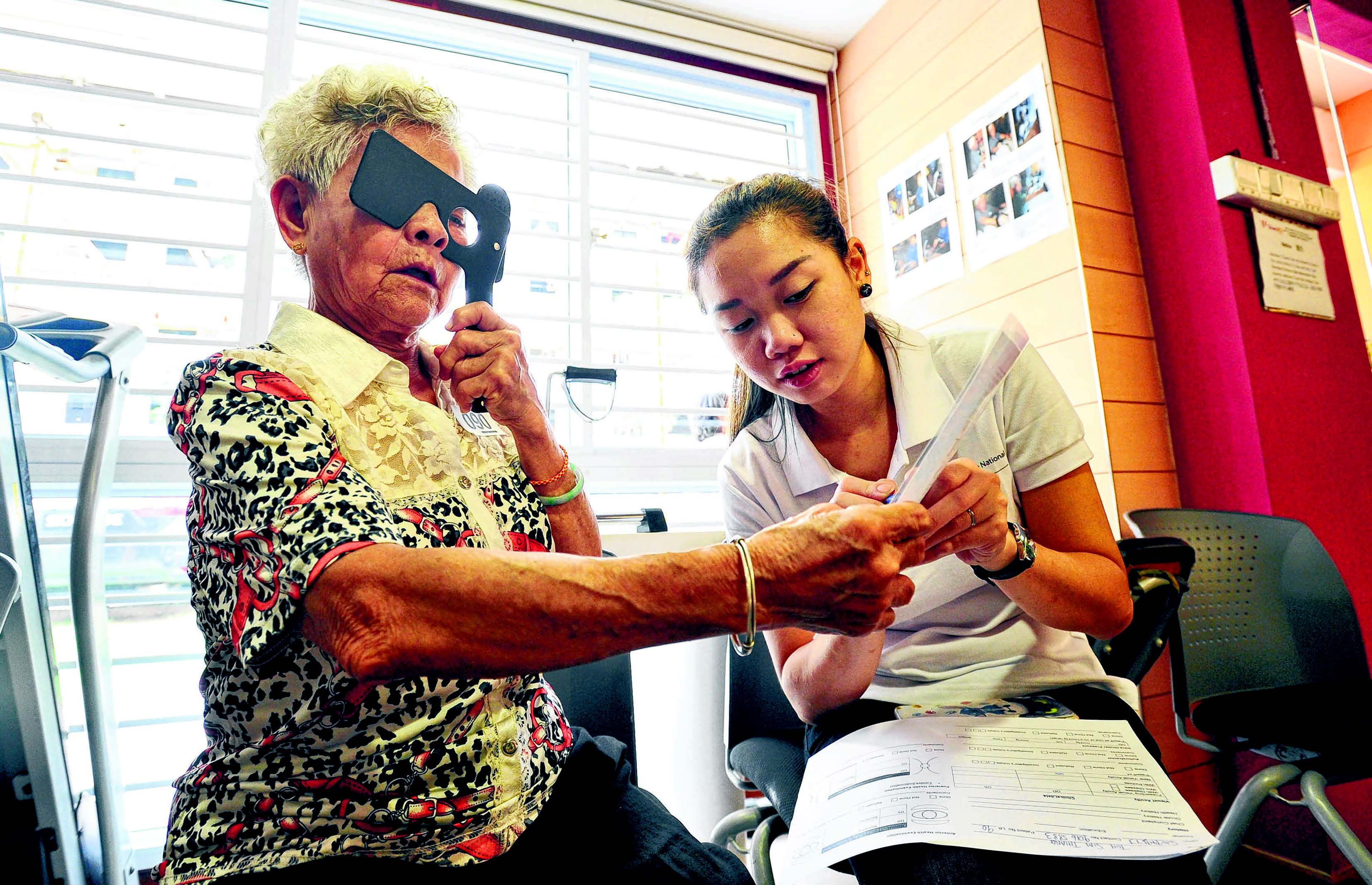  ​getting her eyes checked by nurse Yolane Chew, 24, in the mobile clinic yesterday. Of the 1,800 seniors screened under the project, 1,000 need follow-up treatment. They have been given referrals to seek treatment at hospitals. Their first consultation is free. ST PHOTO LIM YAOHUI